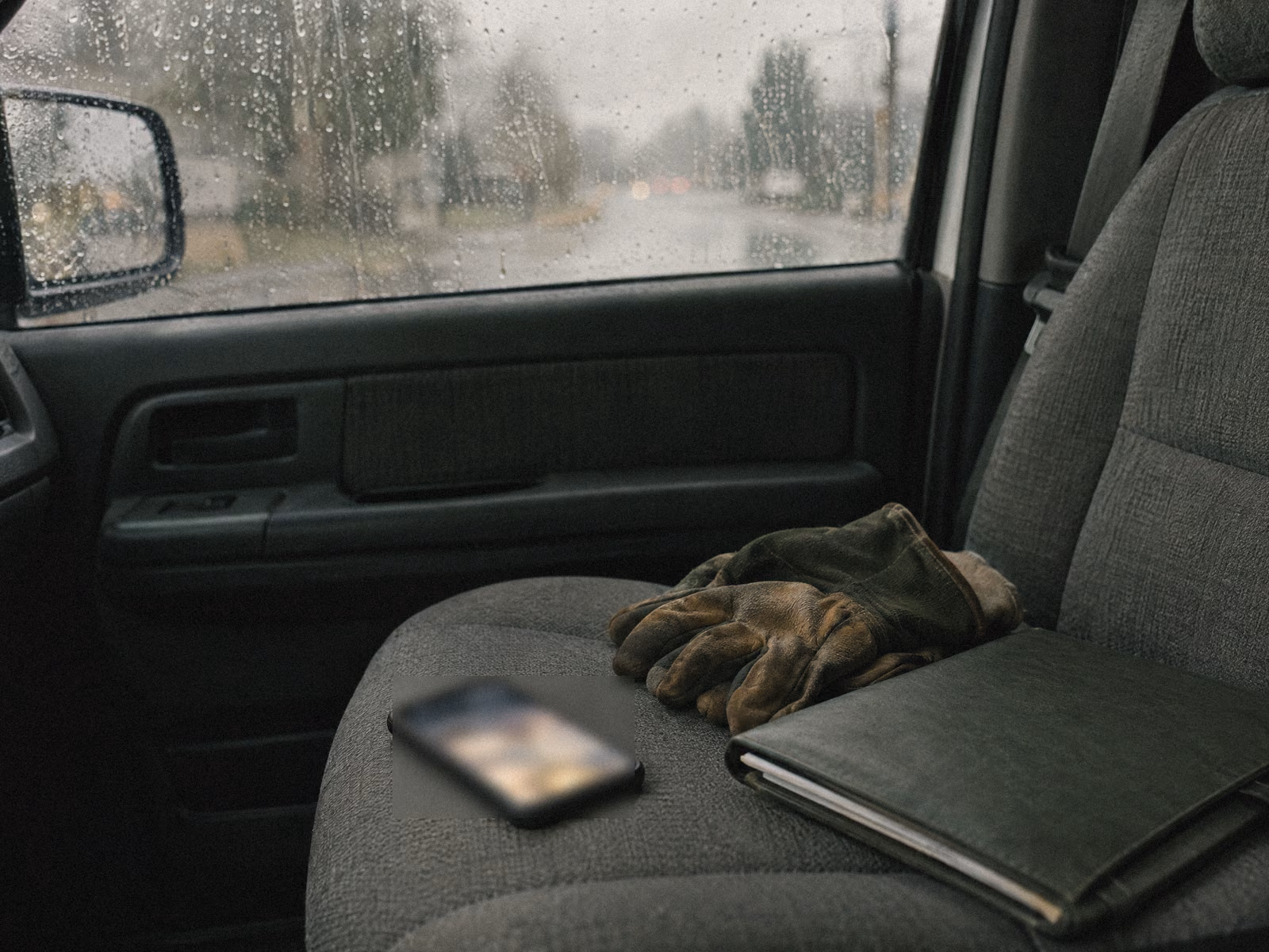 A phone lighting up on the seat of a parked work truck in the rain.